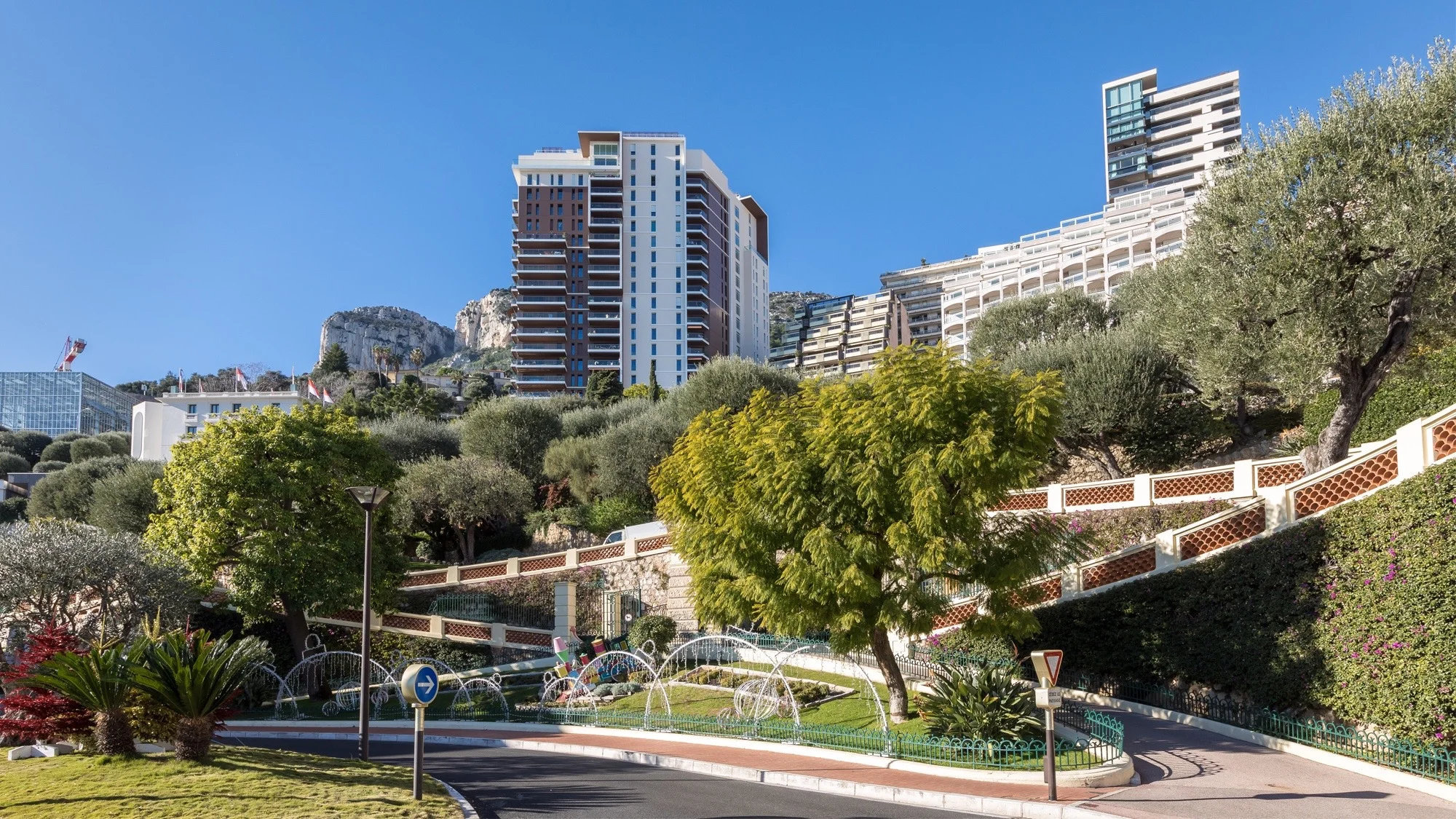 Vue d'une rue avec des immeubles résidentiels colorés et une verdure luxuriante dans le quartier des Moneghetti, Monaco.