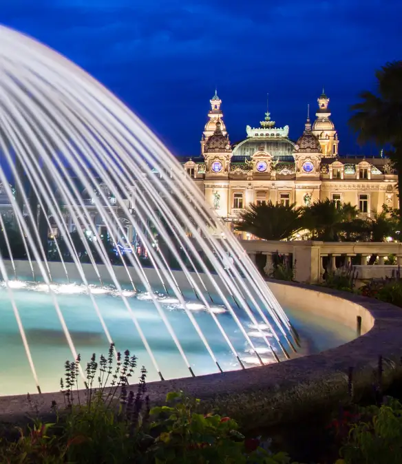 The Monte Carlo Casino photographed at night with a fountain in the foreground